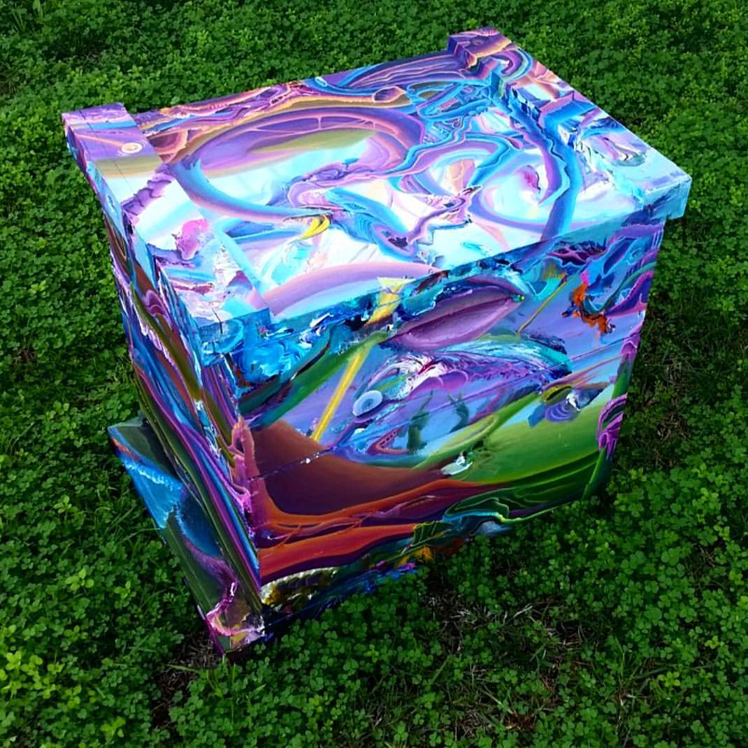Beecasso painted bee box with swirling purple and blue pour-paint design, photographed on grass