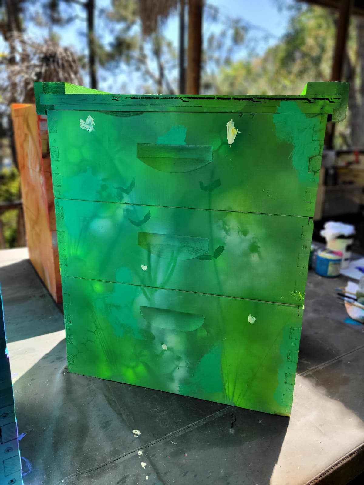 Beecasso painted bee box in bright green with gestural forms, studio setting