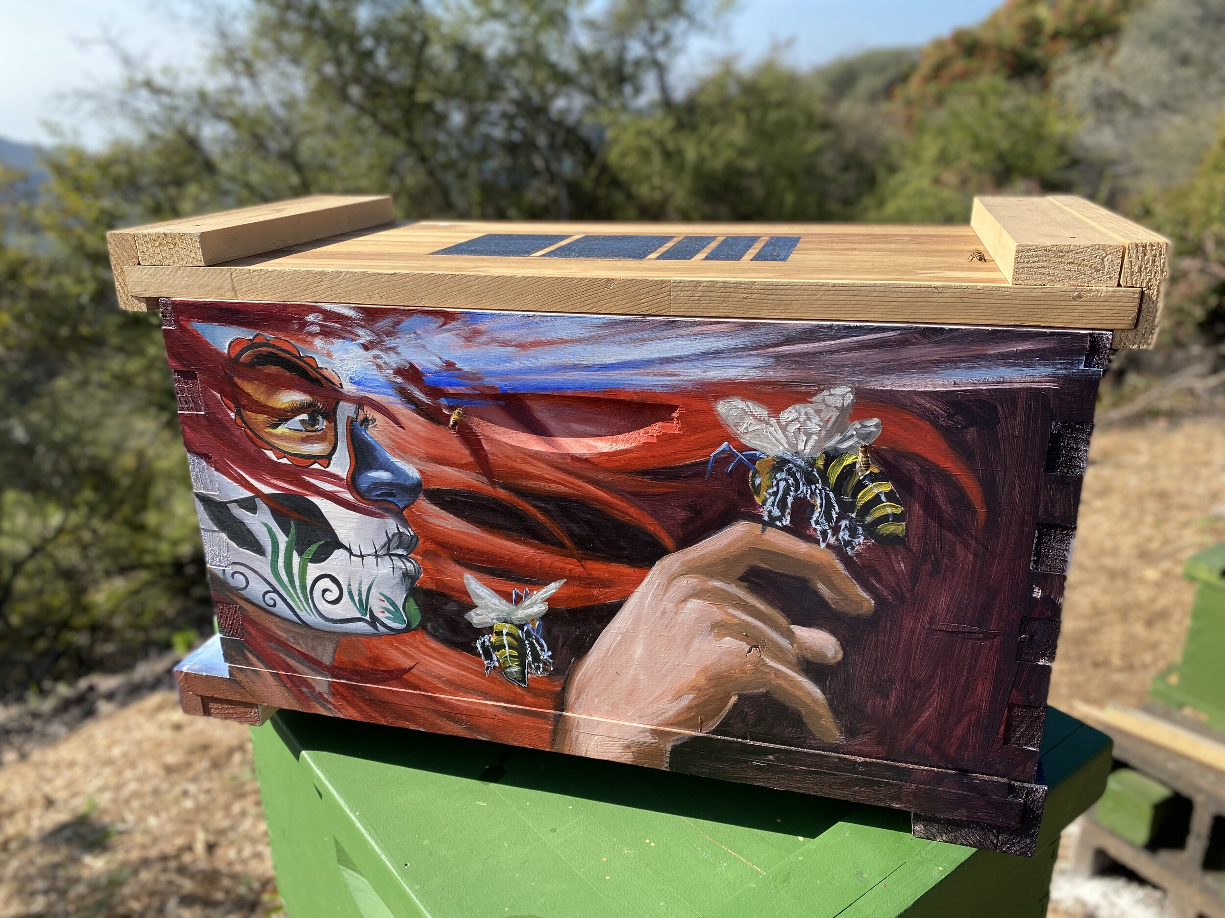 Beecasso bee box painted with Day of the Dead woman in red hair, three-quarter view, bees in art