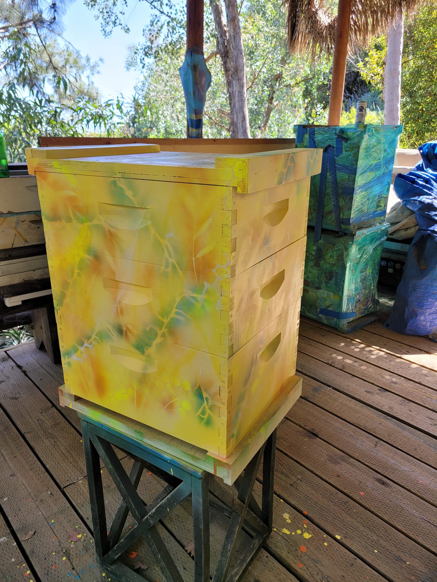 Beecasso painted bee box in golden yellow with leaf and botanical forms, on display stand