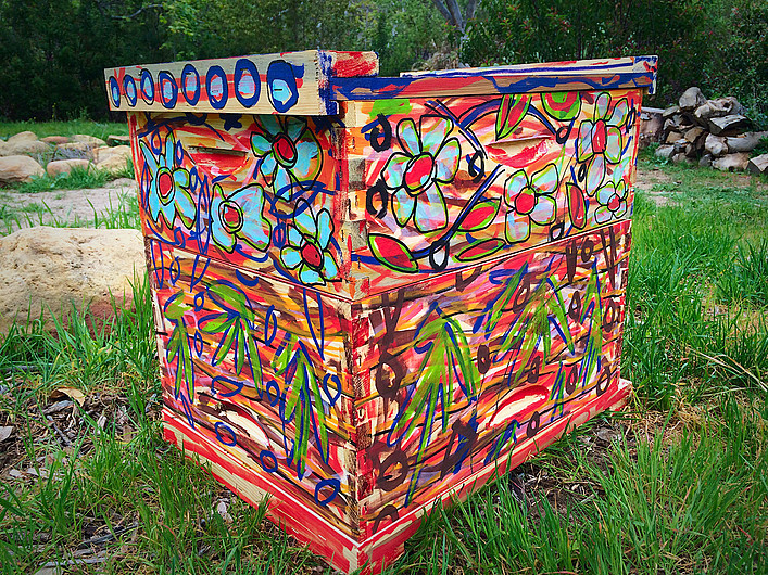 Beecasso bee box covered in red with colorful floral and graffiti forms on all sides