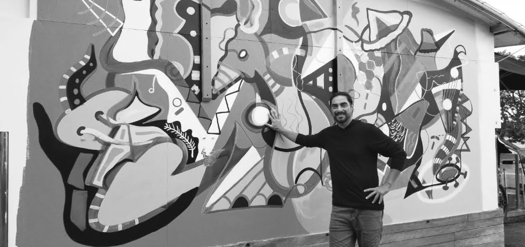 Steve Downs standing in front of the completed New Zealand mural, black and white photograph