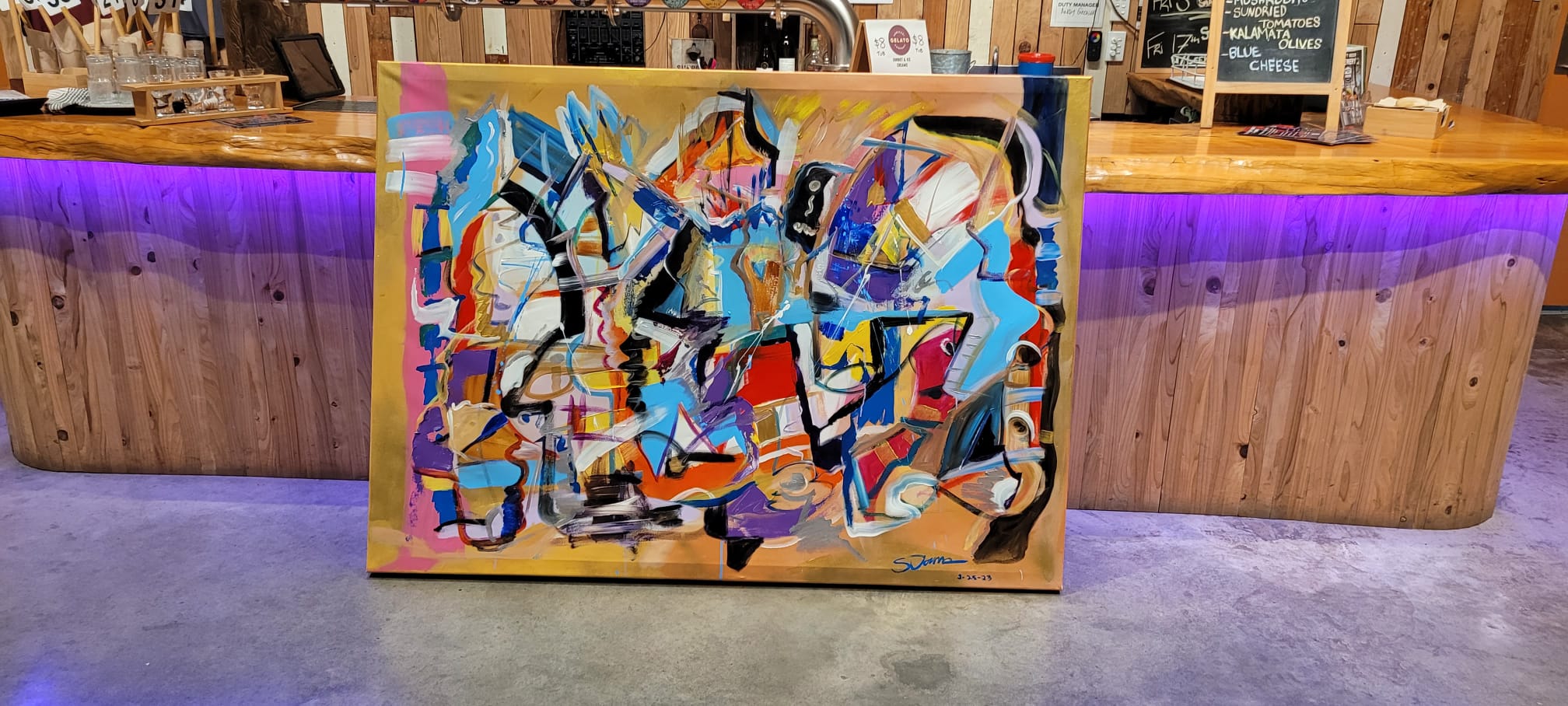 Steve Downs abstract canvas painting displayed against bar counter with purple lighting